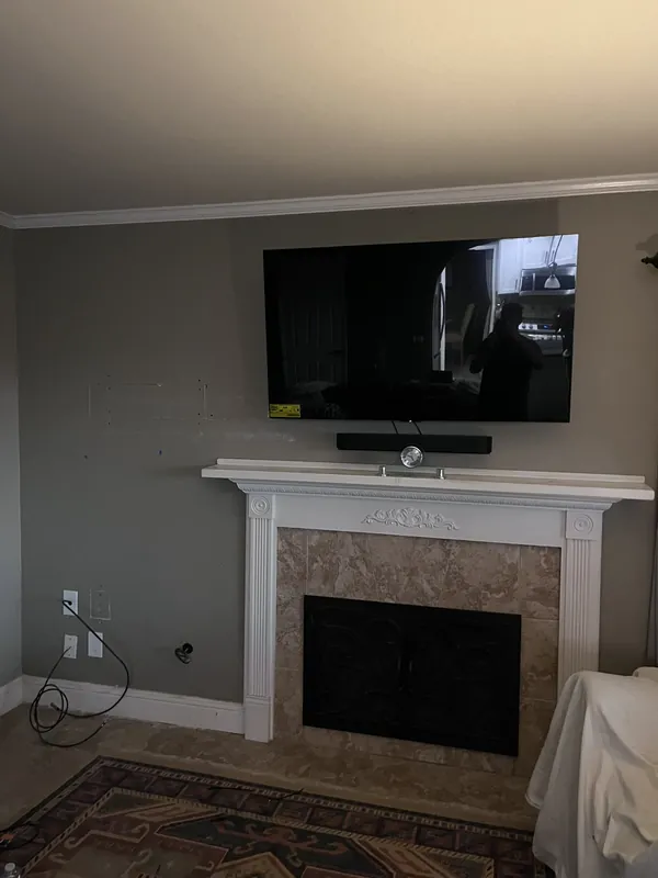 Mounted TV with concealed wiring and soundbar over a fireplace
